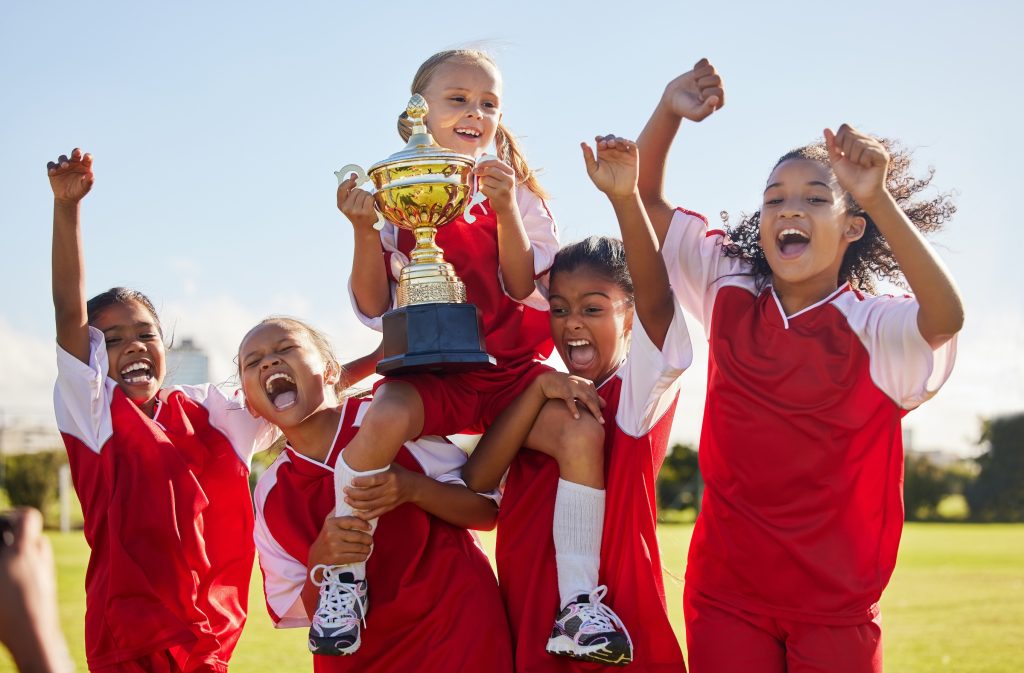 Football, team and trophy with children in celebration