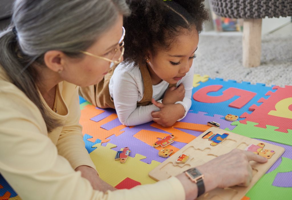 Woman, child with puzzle for support, occupational therapy.