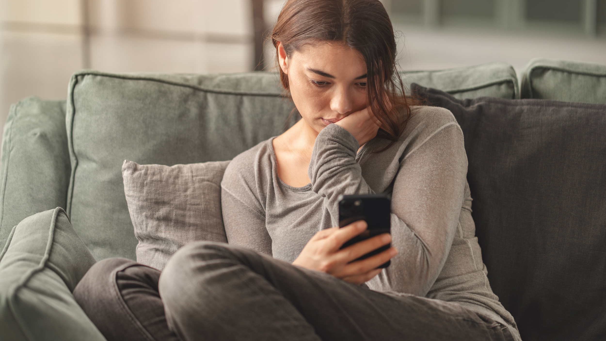 Young woman is on social media looking sad.